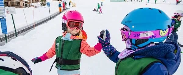 Kids having fun and giving a high five when skiing at Founders Place resort in Utah